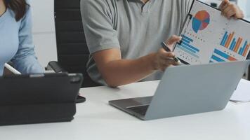 A man and woman are looking at a laptop screen with graphs on it video