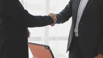 Two business people shaking hands in front of a laptop video