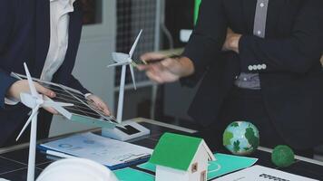 Two people in business attire are working on a table with wind turbines video