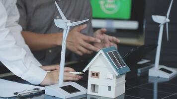 A man is holding a laptop and a small house with wind turbines video
