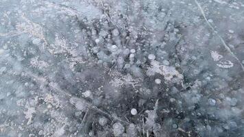 Walking on ice covering a frozen winter river. Cracks, air bubbles and frozen algae are visible in the ice video