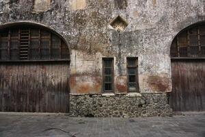 Old weathered building facade, wood doors, stone base, urban setting, historical architecture photo