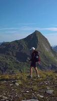 Aerial view of a girl with a backpack traveling through the mountains. Beautiful view of the peaked tops of the Lofoten Islands, Norway, vertical footage video