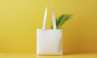 A white tote bag with a green leaf in it is on a yellow background photo