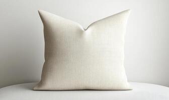 A white pillow with a pattern on it sits on a white surface photo