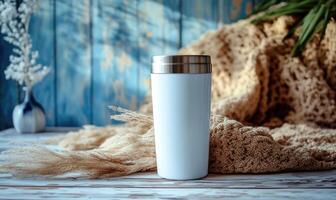 A white coffee cup sits on a table next to a blanket photo