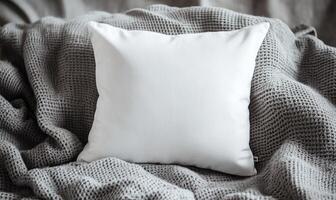 A white pillow with a pattern of a zebra is on a bed with a gray blanket photo