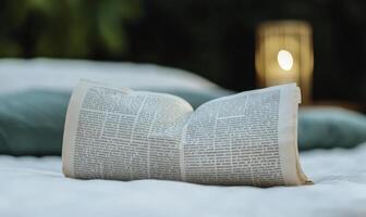Open Book on White Bedspread with Green Pillows and Soft Ambient Light Creating a Cozy Reading Atmosphere in a Relaxing Environment photo
