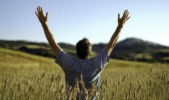 A man in a field with his hands up photo
