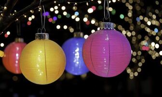 Three colorful paper lanterns hanging from a tree photo