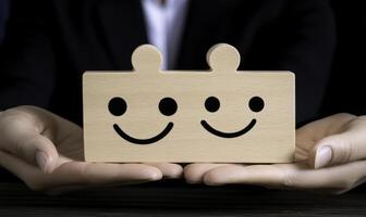 Wooden block with two happy face engravings held by hands representing joy, connection, teamwork, and positive emotions in a professional setting photo