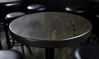 Close-Up View of Round Wooden Table with Dark Finish Surrounded by Black Stools in a Cozy Dining Space with Dim Lighting photo