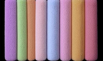 Colorful Fabric Rolls Displayed in a Row, Featuring Soft Textures in Pastel Shades of Pink, Green, Purple, and Orange on a Dark Background photo