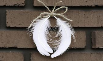 White feather decoration hanging on a rustic brick wall with a jute twine bow creating a charming and cozy atmosphere for home decor photo