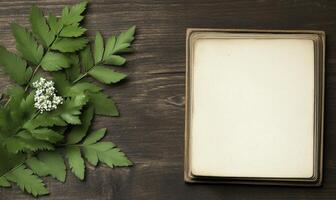 Fresh green leaves and delicate white flower on wooden table with blank square for handwritten notes or artistic inspiration in a natural setting photo