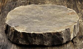 Circular gray stone on rustic wood surface with natural texture, showcasing the simplicity and beauty of nature's raw materials in a minimalist aesthetic. photo