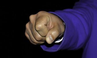 Close-up of a clenched fist symbolizing determination and strength in a dark environment showcasing human emotion and power dynamics in society photo