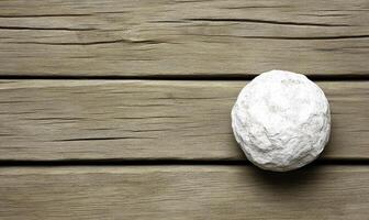 Natural white stone resting on a rustic wooden surface, showcasing the contrast between smooth stone and textured wood grain in serene composition photo