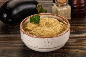 A bowl of food sitting on a table next to an eggplant photo