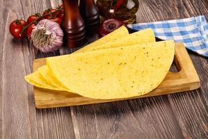 A tortilla on a cutting board with a knife and other ingredients photo