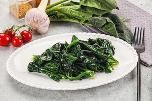 Spinach with garlic and tomatoes on a white plate photo