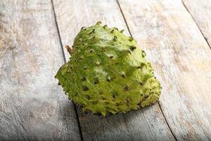 A single green fruit on a wooden surface photo