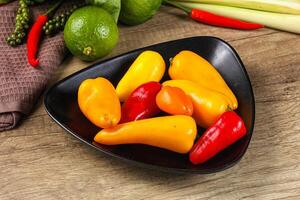 A bowl of peppers and limes on a table photo