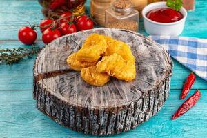 A wooden stump with fried chicken on it photo