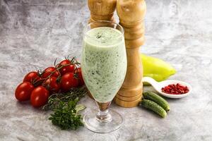 A glass of green smoothie with a pepper and tomatoes photo