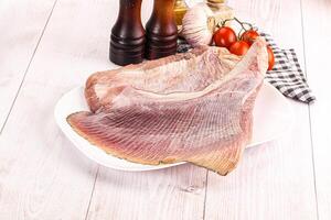 A piece of fish on a plate with a knife and other ingredients photo