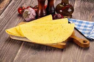 A tortilla on a cutting board with tomatoes, onions and spices photo