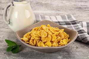 Corn flakes and milk in a bowl on a wooden table photo