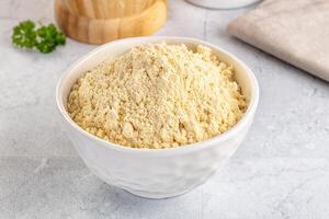A bowl of flour and a spoon next to a wooden spoon photo
