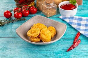 A bowl of fried chicken nuggets on a blue table photo