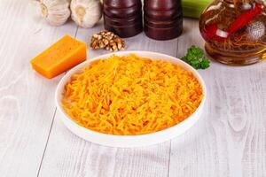 A bowl of shredded cheese next to garlic, onions and other ingredients photo