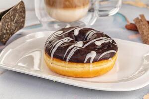 A chocolate donut on a plate with a cup of coffee photo