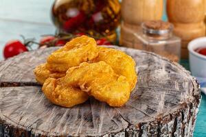 A pile of fried chicken nuggets on a wooden table photo