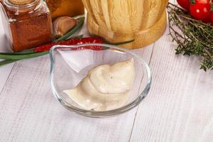 A bowl of dressing on a table with a bottle of ketchup photo
