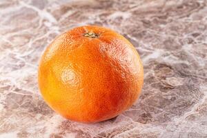 A single orange on a marble surface photo