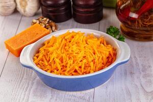 A bowl of shredded cheese next to a bottle of vinegar photo