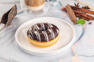 A chocolate donut on a plate with coffee and spices photo