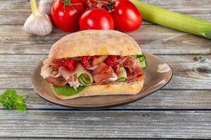 A sandwich on a plate with tomatoes and other vegetables photo