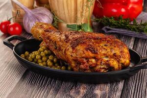 A large chicken in a pan with peas and tomatoes photo