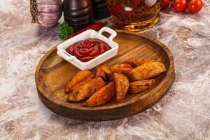 A wooden plate with potatoes and ketchup on it photo