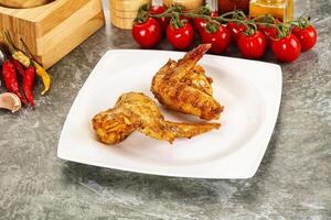 A plate of chicken wings on a counter with a bottle of sauce and a bottle of ketchup photo