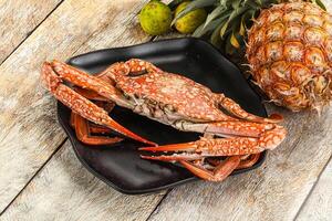 A crab on a plate with a pineapple and some other fruit photo