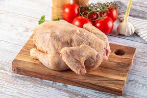 A chicken on a cutting board with tomatoes and garlic photo
