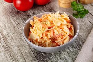 A bowl of coleslaw on a table next to tomatoes photo