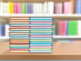 Two stacks of books on a table, blurred library background. photo