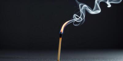 Burning matchstick with smoke on black background. photo